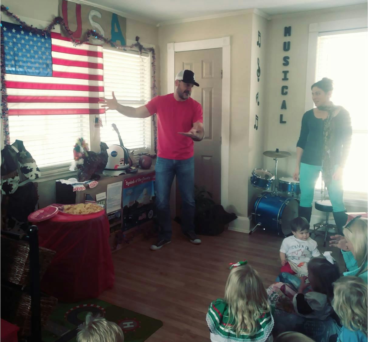 Adults standing in a room with children seated on the floor