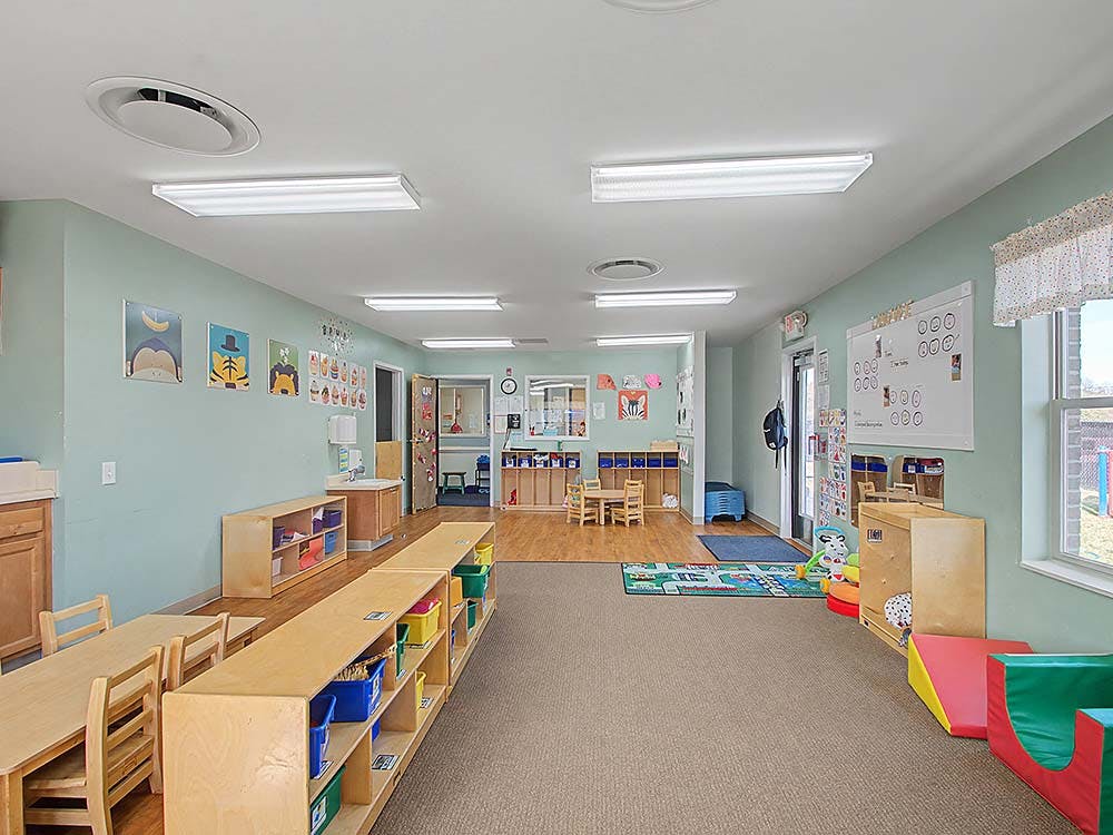 Empty classroom with tables, chairs, and shelves against light blue walls