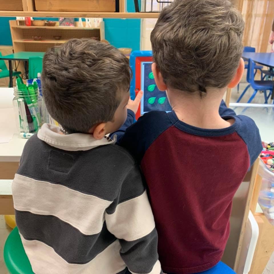 Two children looking at a tablet in a classroom