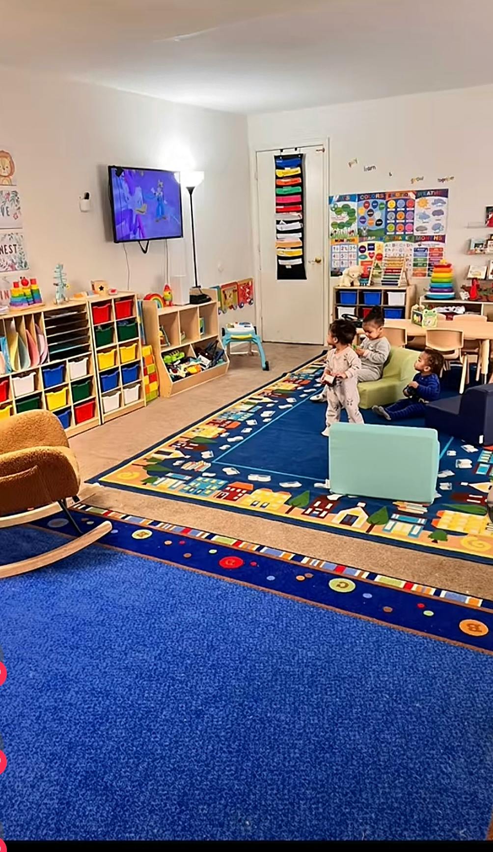 Three young children watching television in a play area