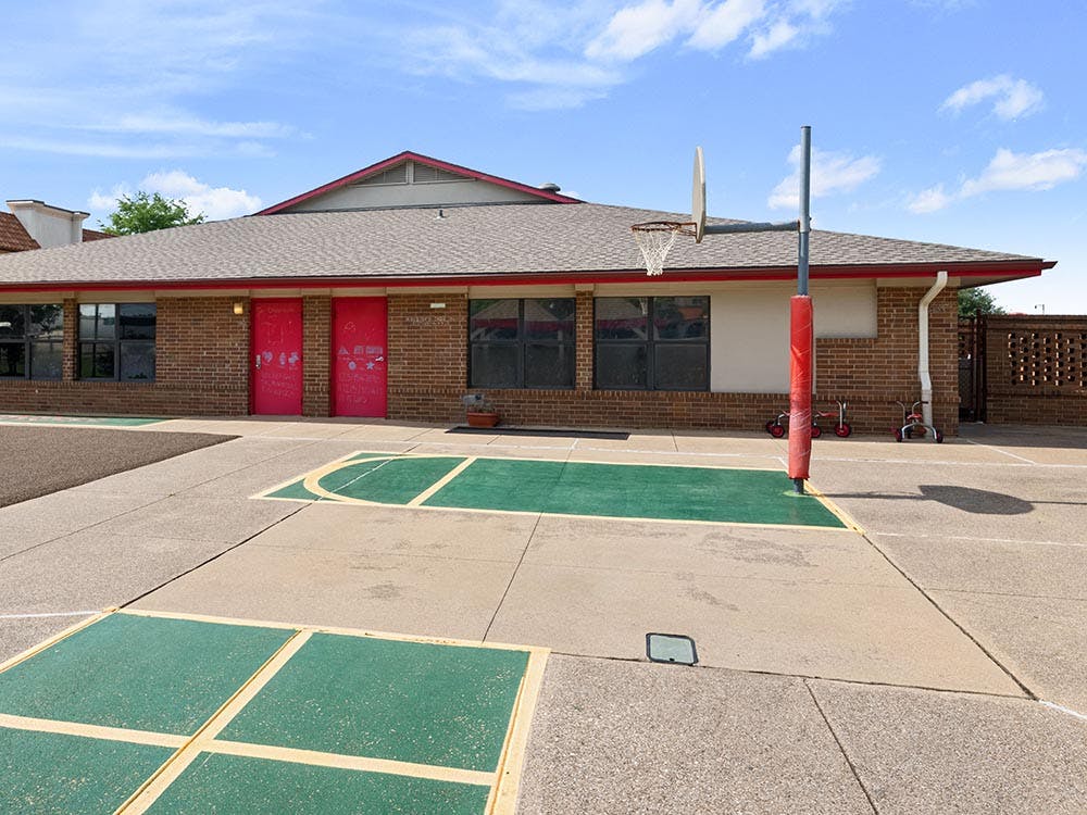 Basketball court and playground in front of a brick building