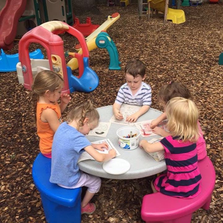 Children drawing at a table outdoors