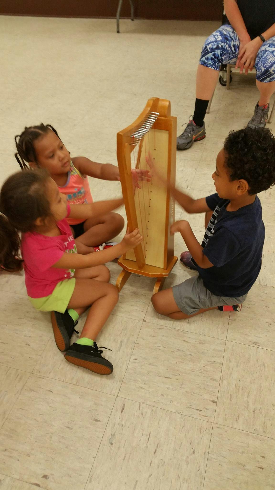 Three children playing a small harp