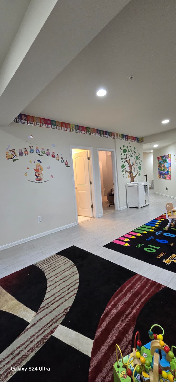 Playroom with alphabet and learning decals on walls and colorful rugs on the floor