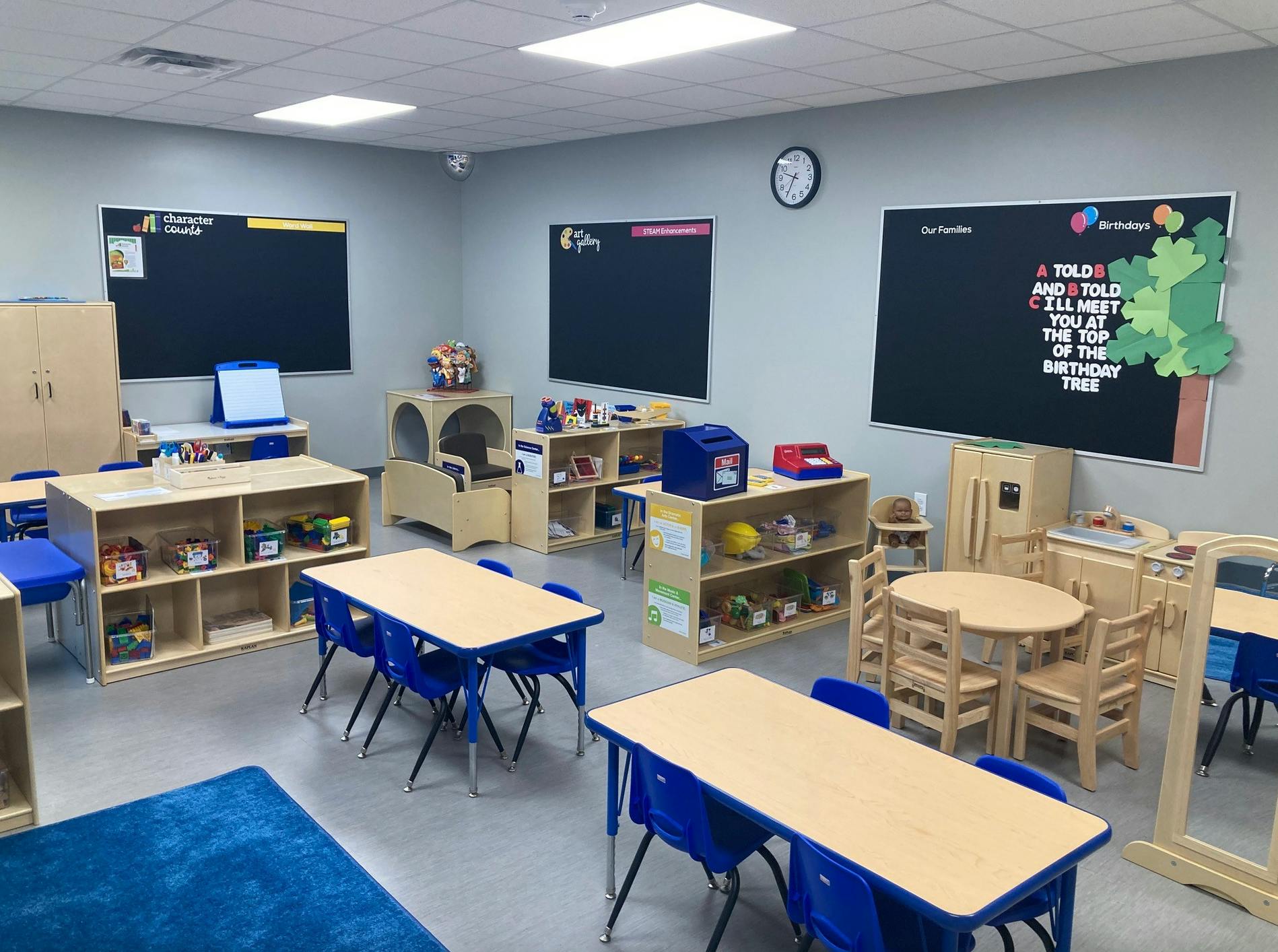 Classroom with small tables and chairs, shelves with toys, and blackboards