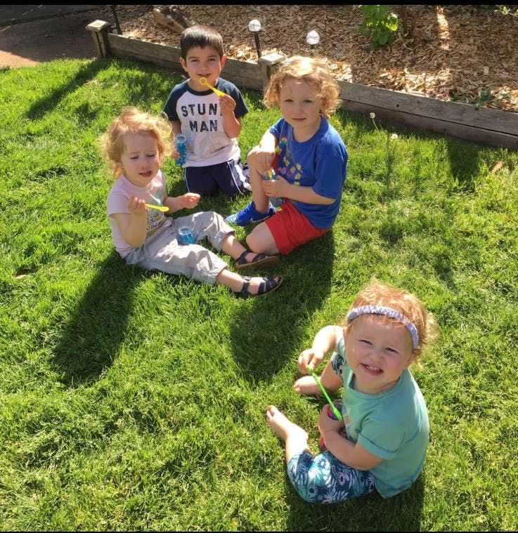 Four children sitting on grass with bubble wands