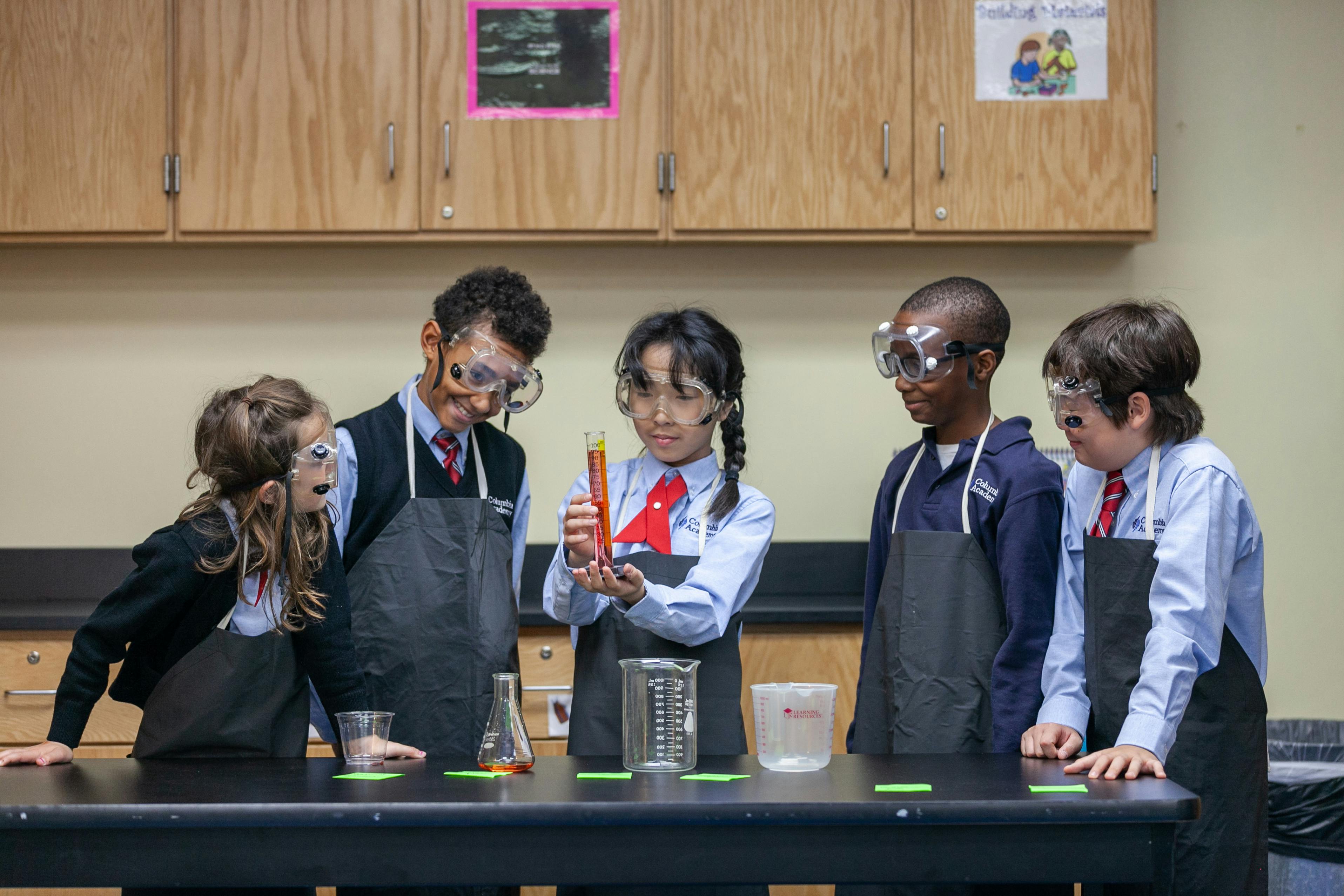 Children in safety goggles and aprons doing a science experiment