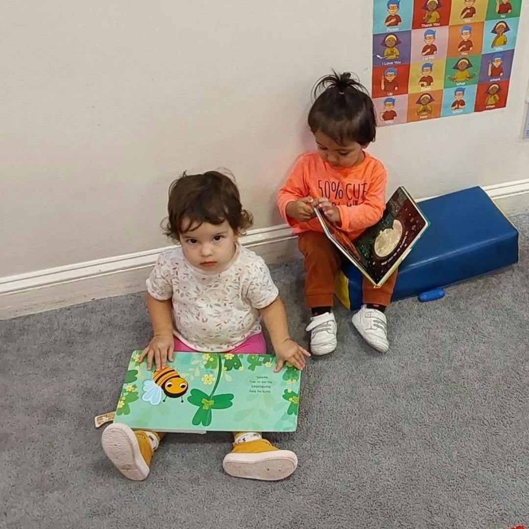 Two children sitting on the floor with books