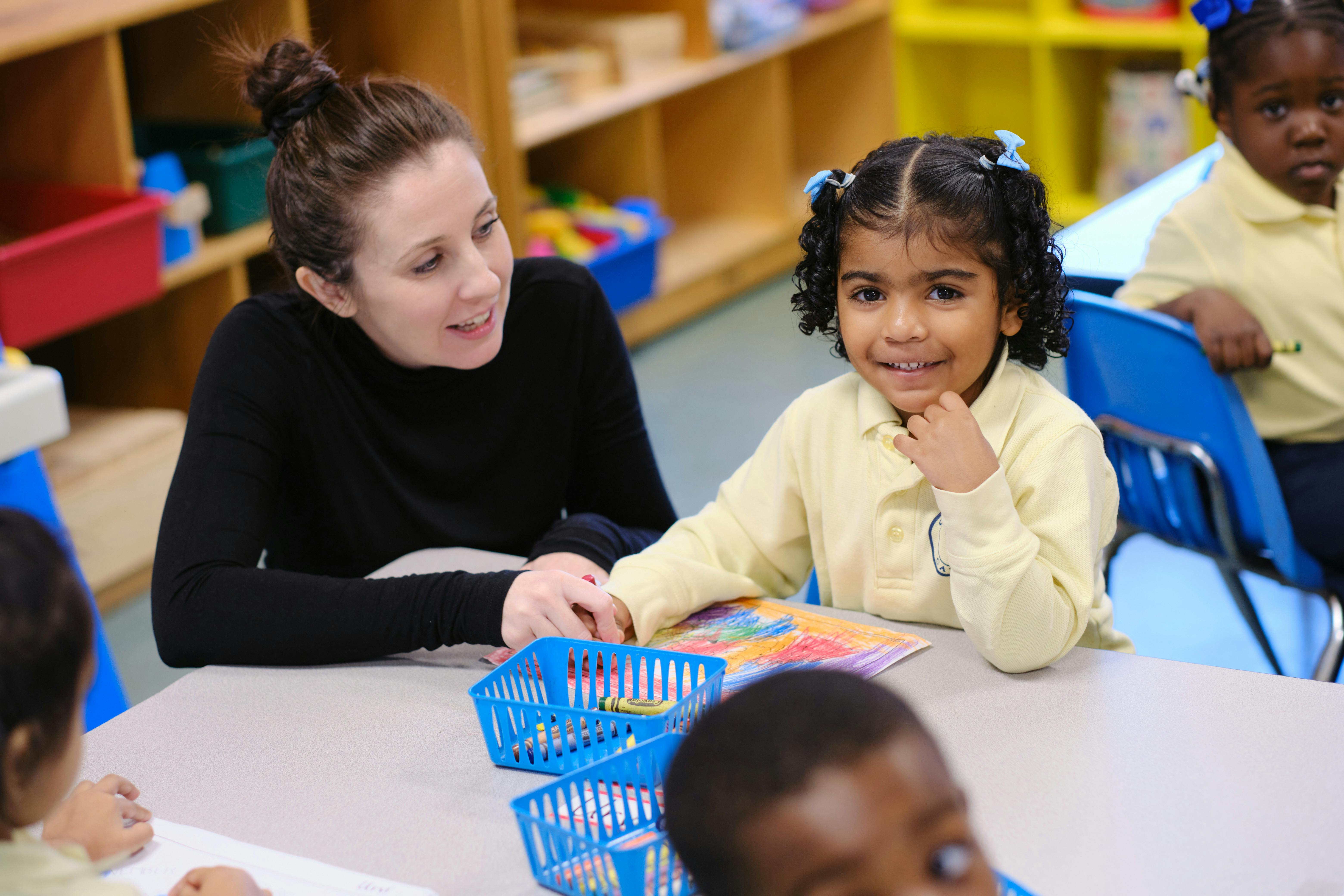 Adult and child sitting at a table in a classroom