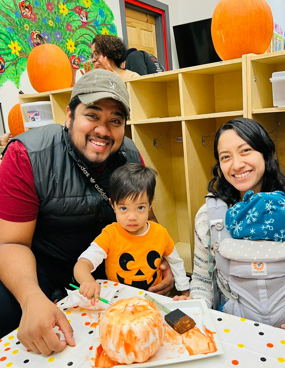 Two adults and a child painting a pumpkin