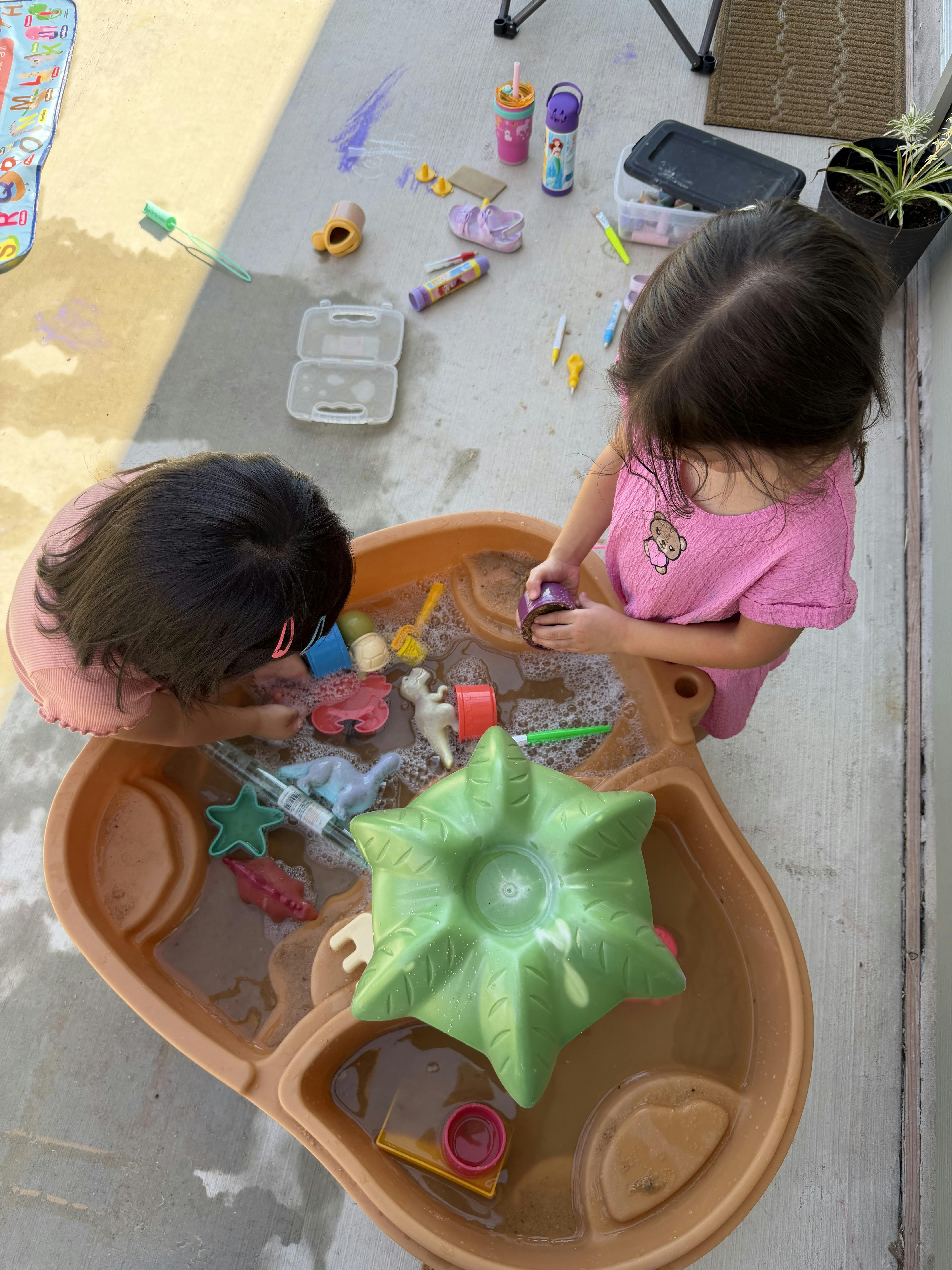 Two children playing with toys in a water table