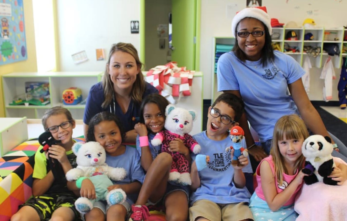 Two adults and five children holding stuffed animals