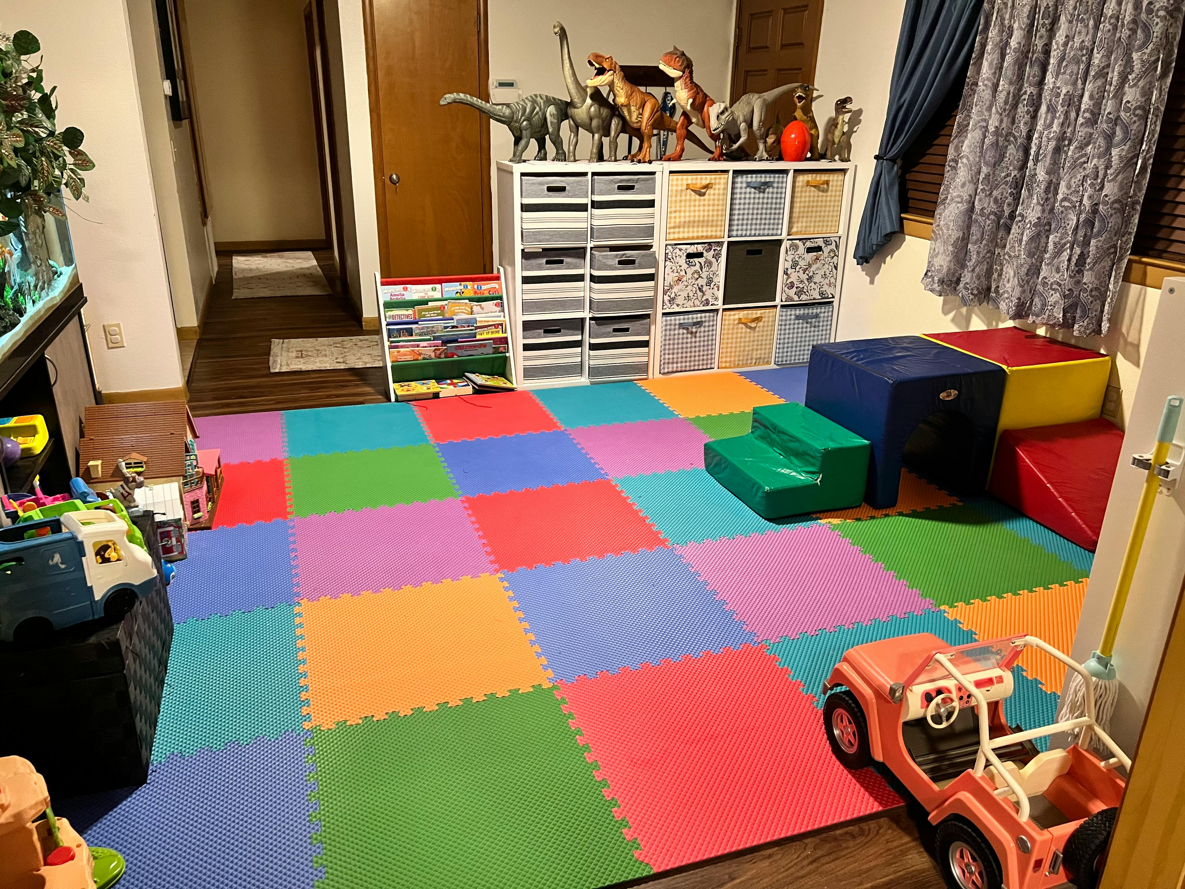 Playroom with colorful interlocking floor mats, toy storage, and play equipment
