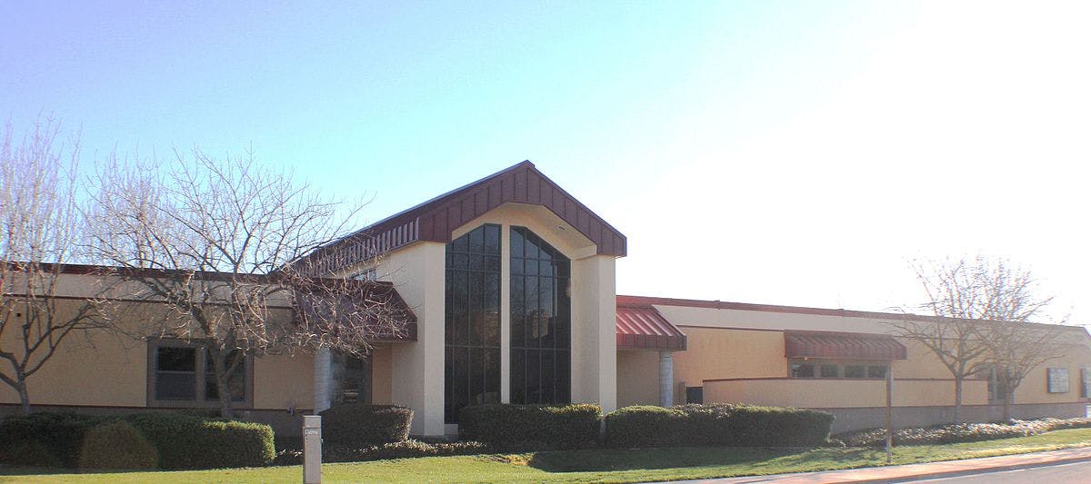 Building with a large arched window and red-tiled roof sections
