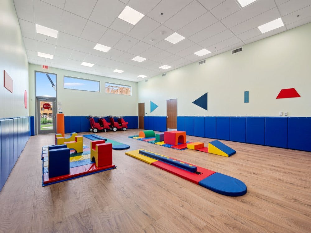 Indoor play area with colorful soft play equipment on a wood floor