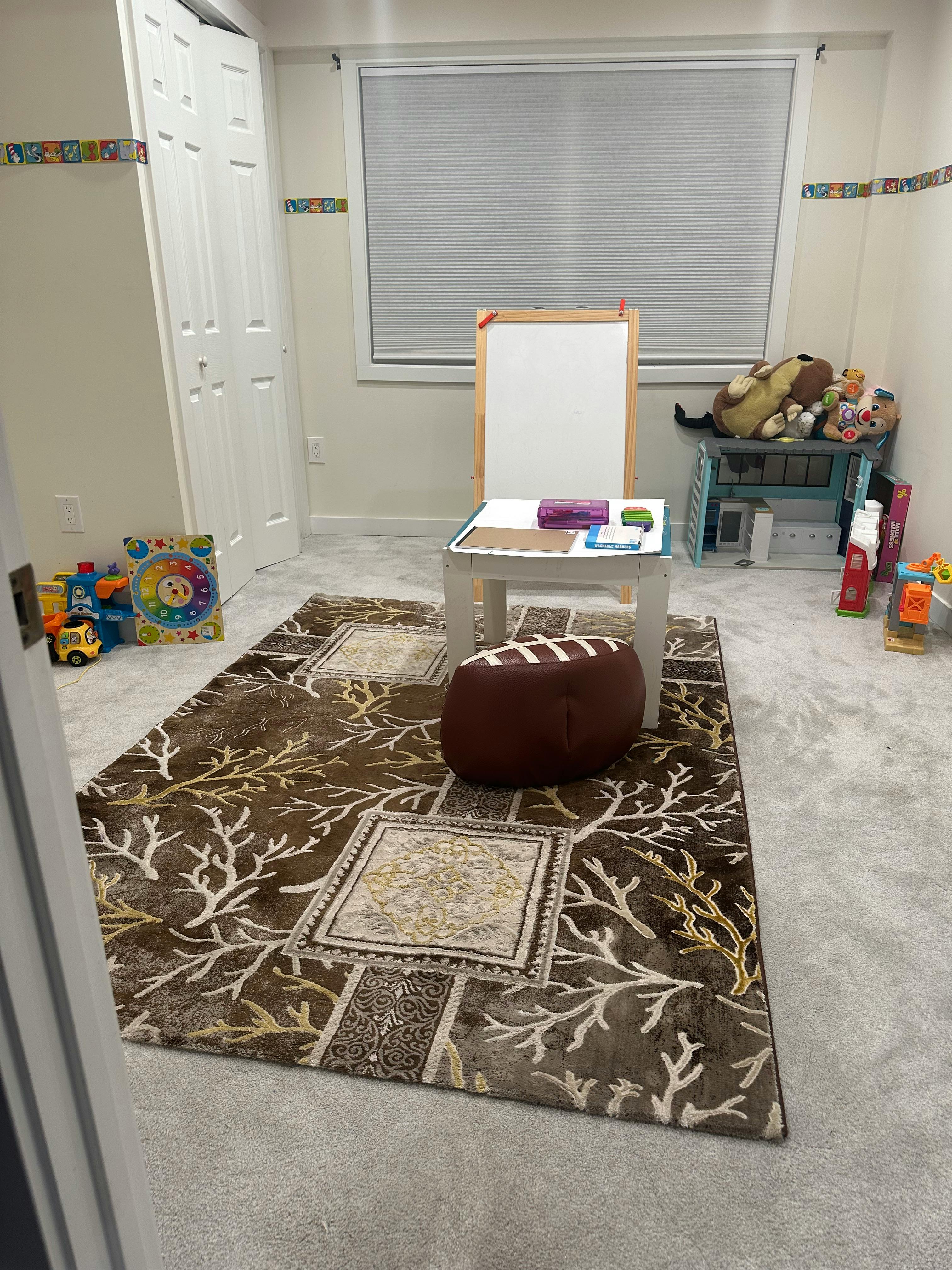 Playroom with a rug, small table, easel, and toys