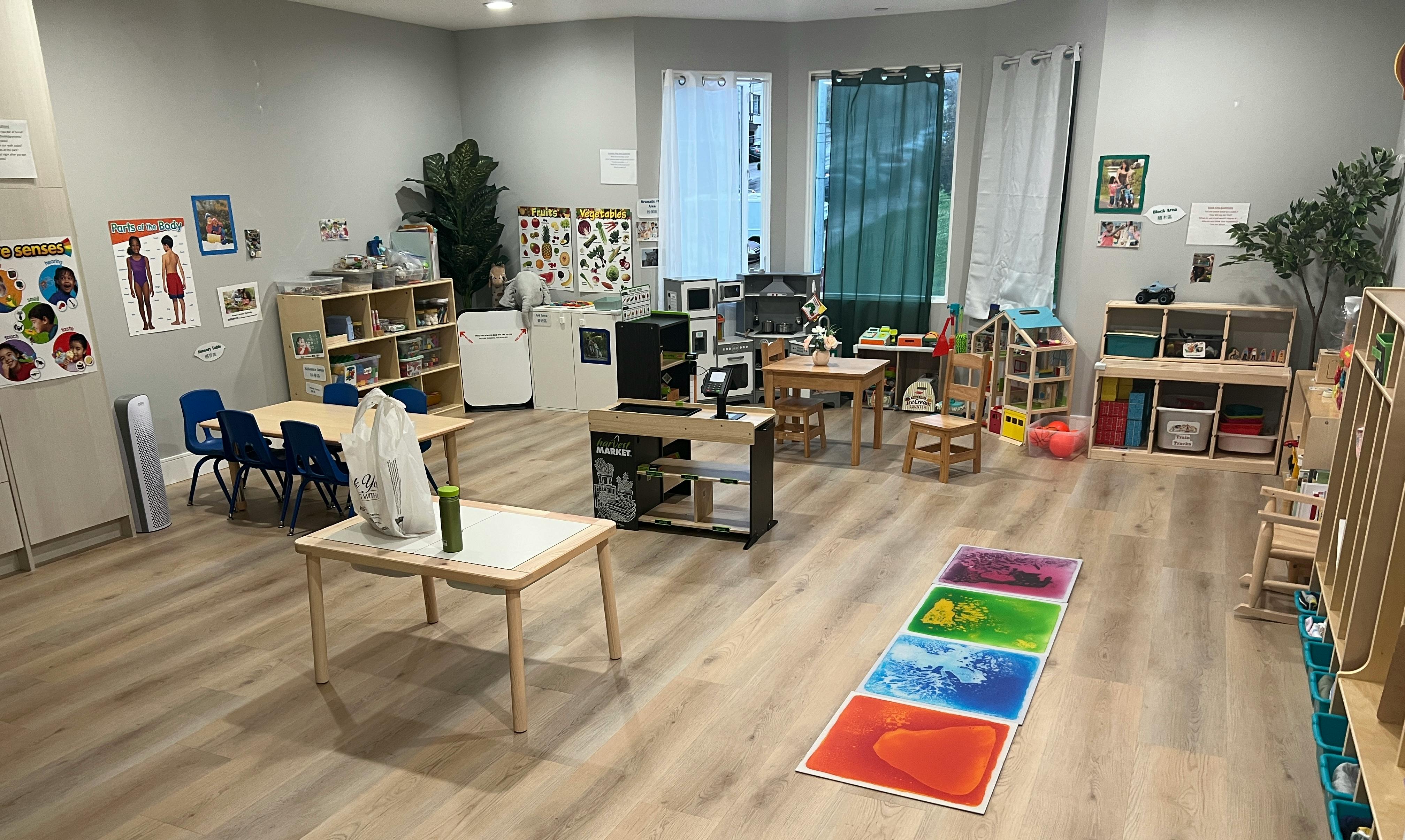 Classroom with tables, chairs, shelves, and a colorful mat on the floor