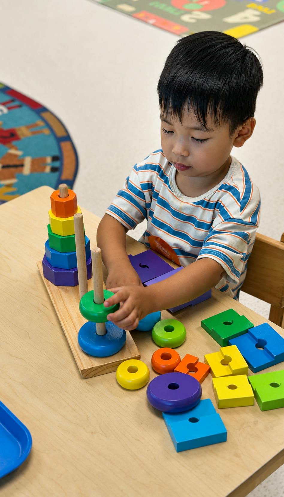 Child playing with a wooden stacking toy at a table