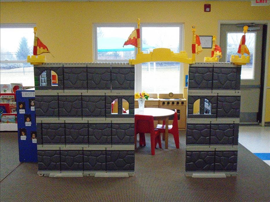 Playroom with a castle facade, red chairs, and a play kitchen