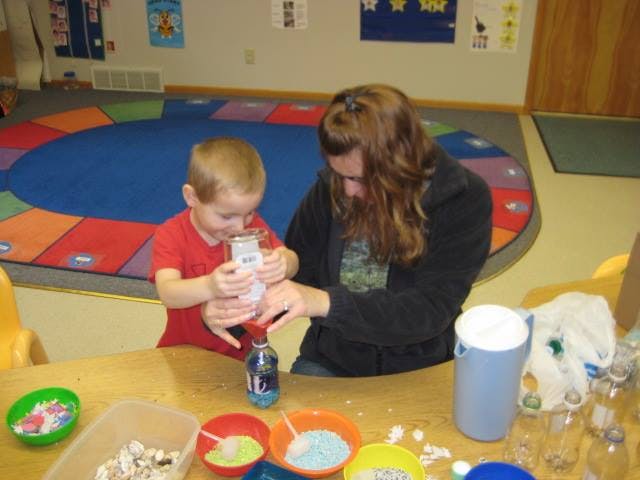 Adult and child pouring contents from a box into a bottle