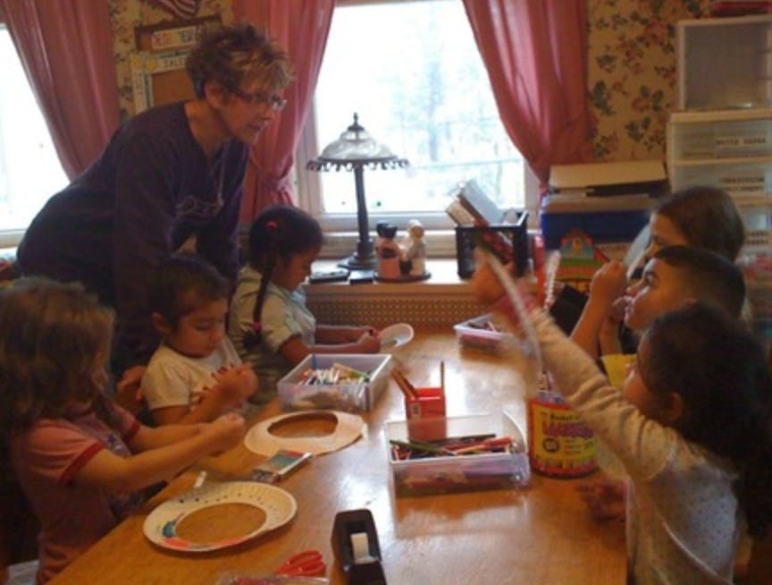 Adult supervising children doing crafts at a table