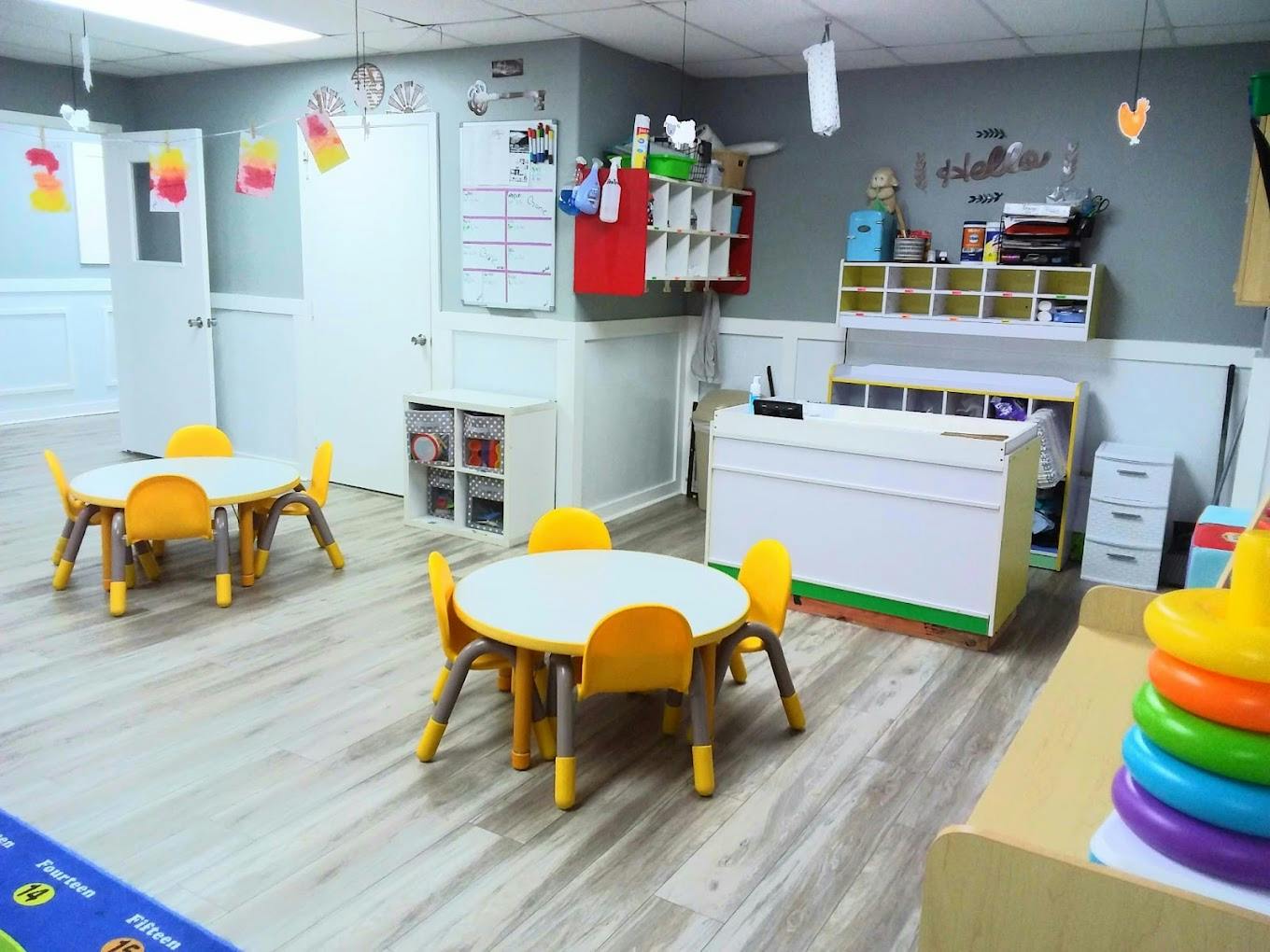 Two small round tables with yellow chairs in a classroom