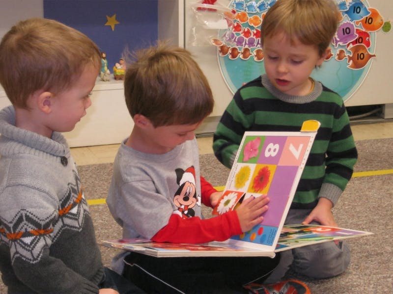 Three children looking at a colorful book