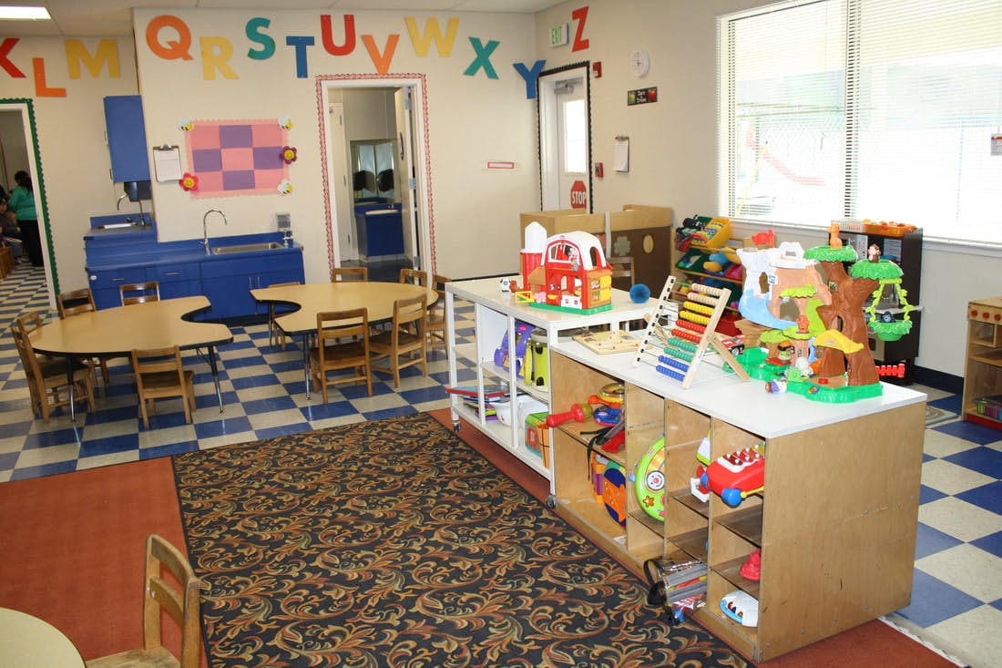 Classroom with tables, chairs, and shelves of toys