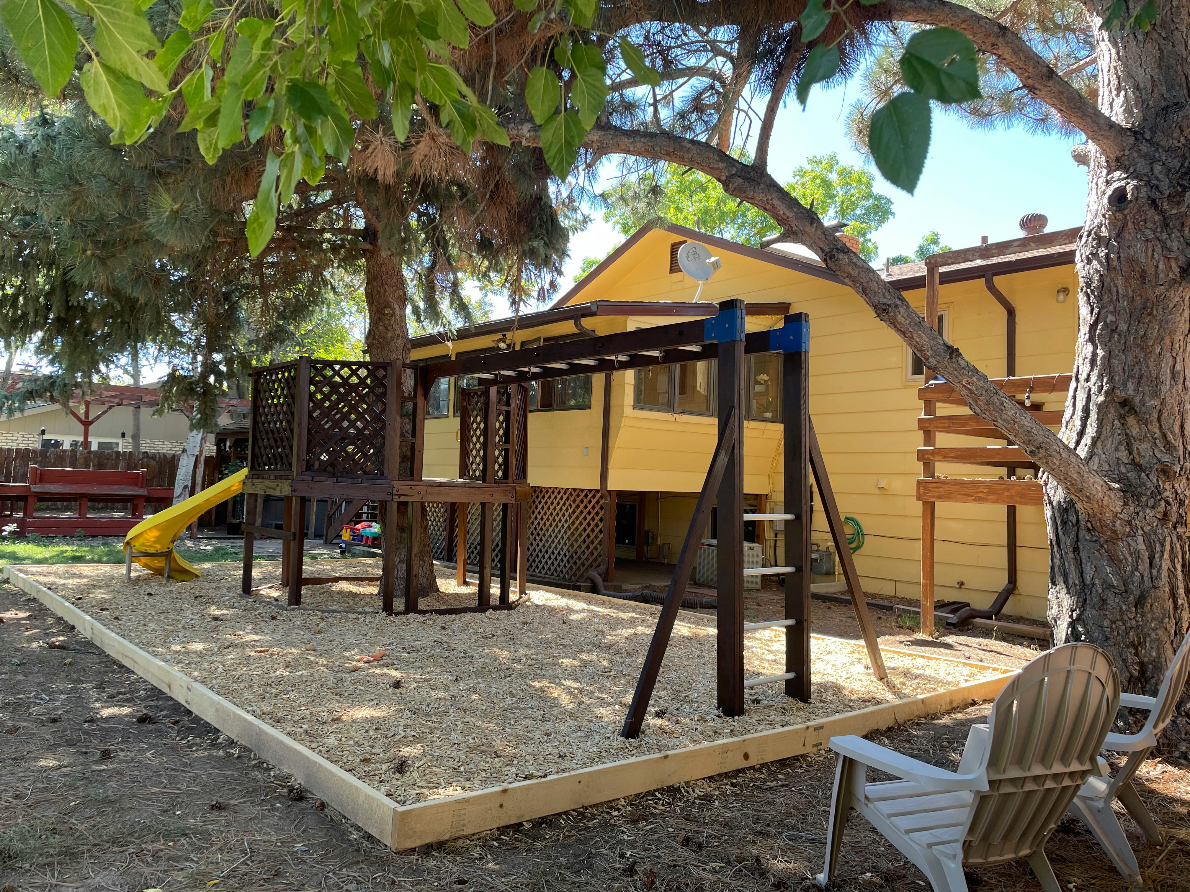 Outdoor playground with a slide, monkey bars, and a wooden play structure
