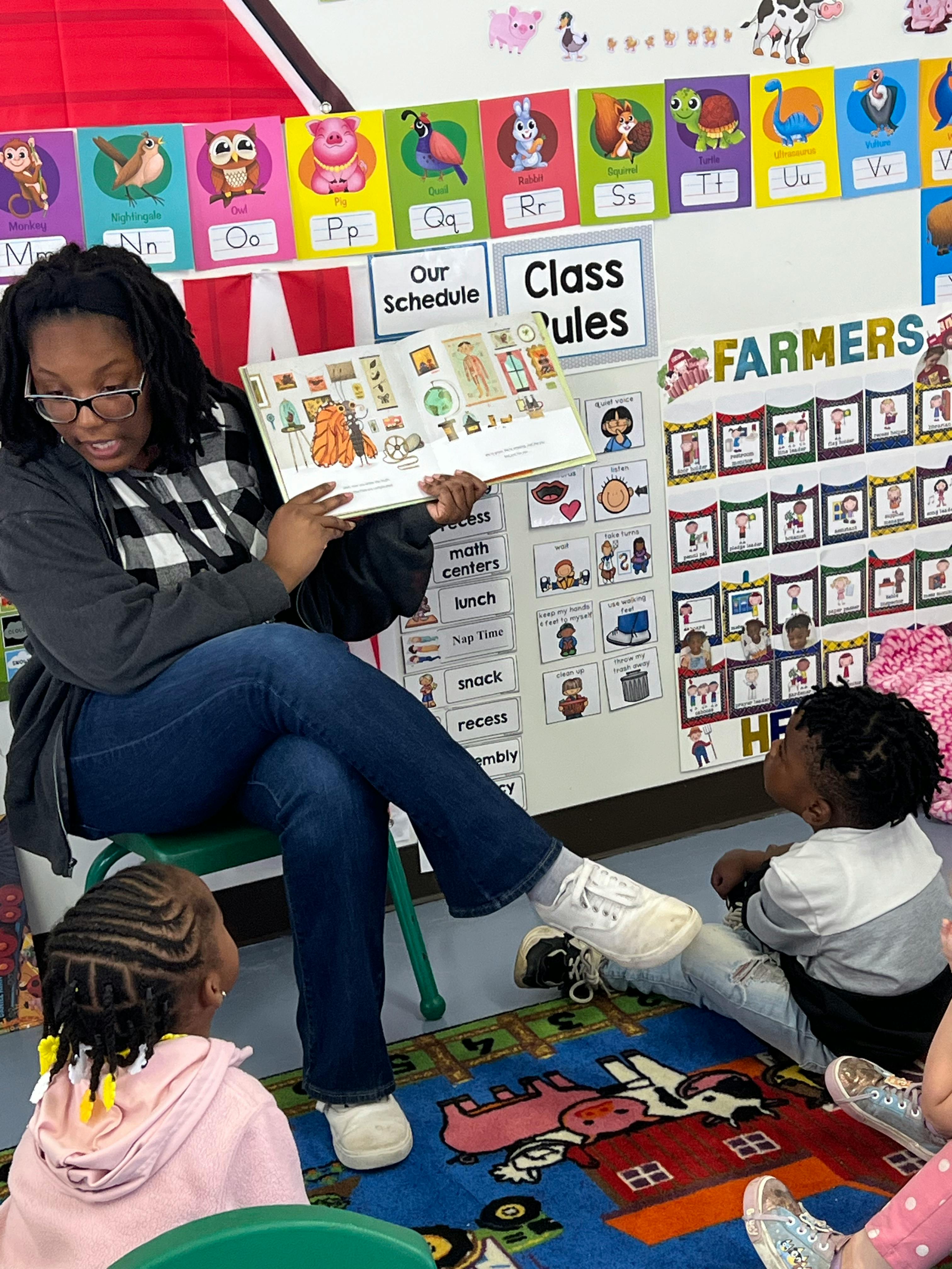 Adult and two children looking at a book in a classroom