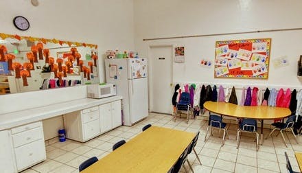 Classroom with tables, chairs, coat rack, and bulletin board