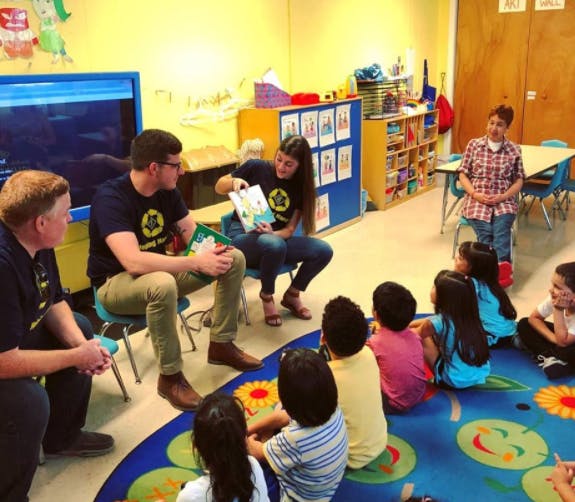 Adults reading to children in a classroom