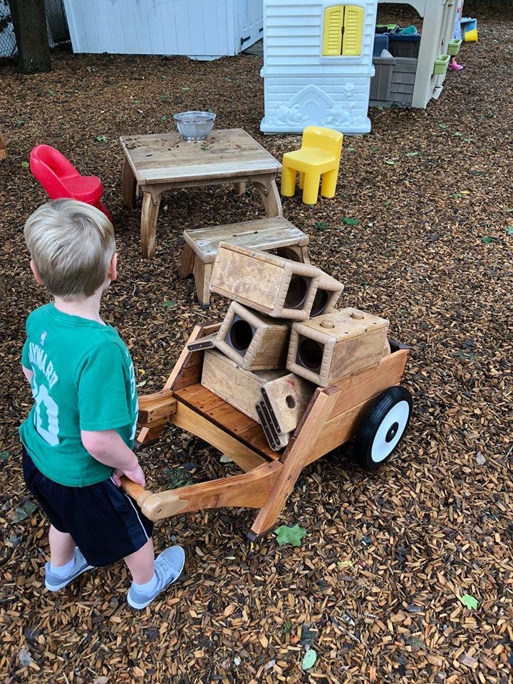 Child pulling a wooden wagon filled with wooden blocks