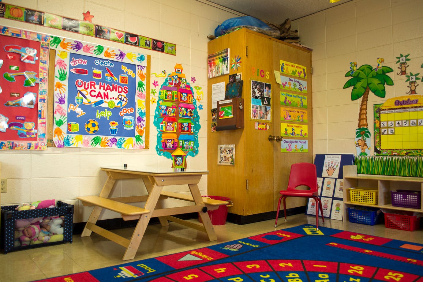 Classroom with small picnic table, colorful rug, and wall decorations