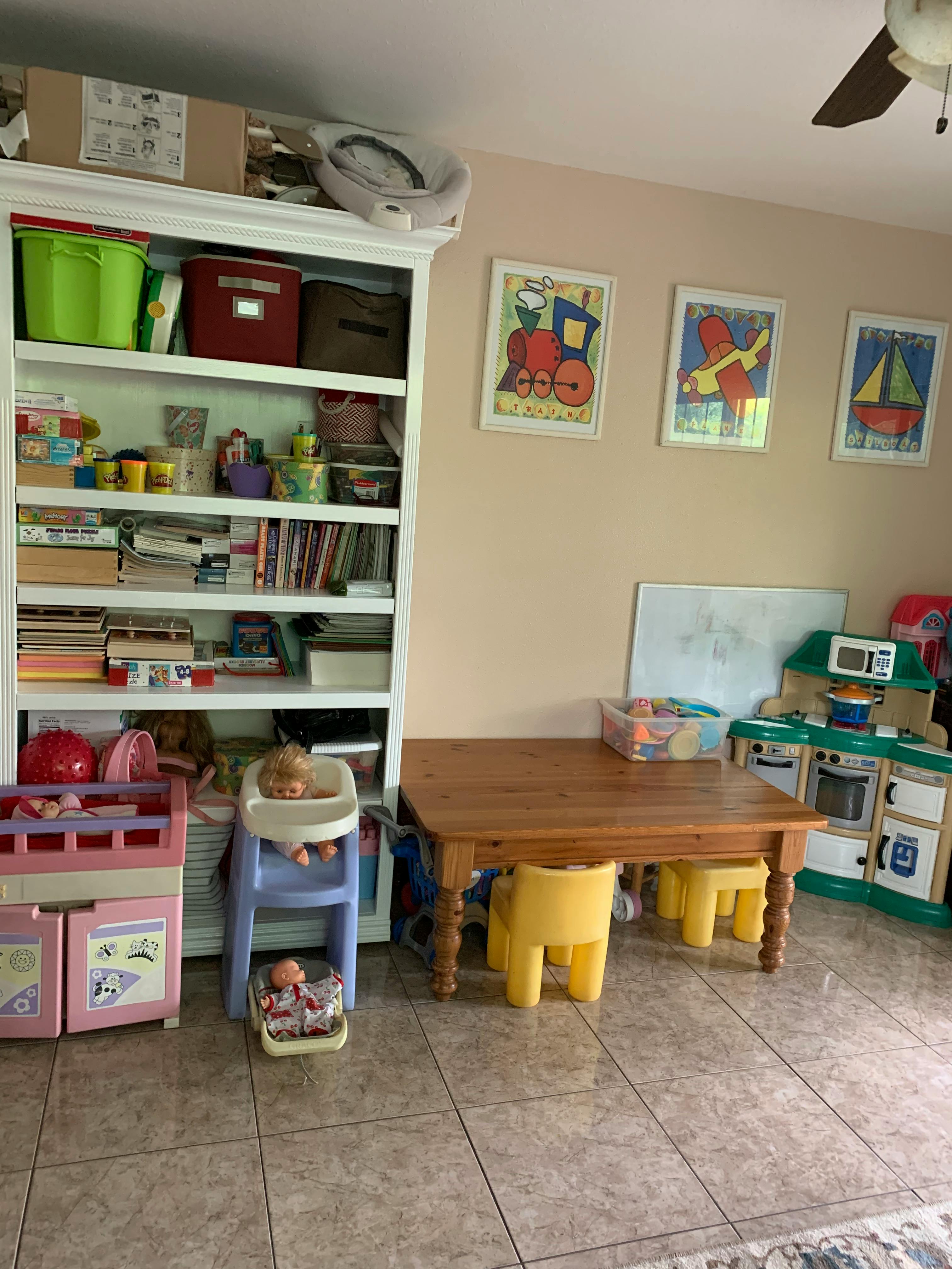 Playroom with bookshelf, small table and chairs, and toy kitchen