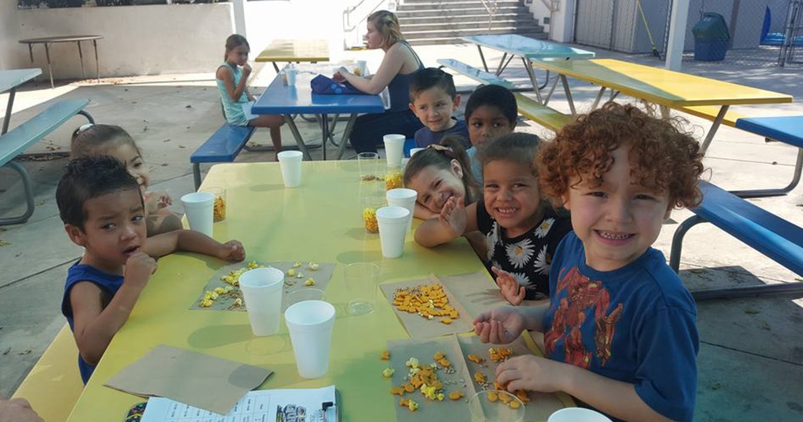 Children sitting at a table with snacks and eating snacks