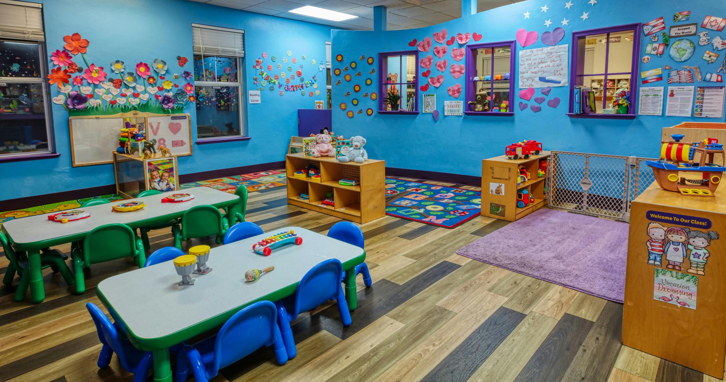 An empty children's classroom with colorful decorations, small tables, and chairs