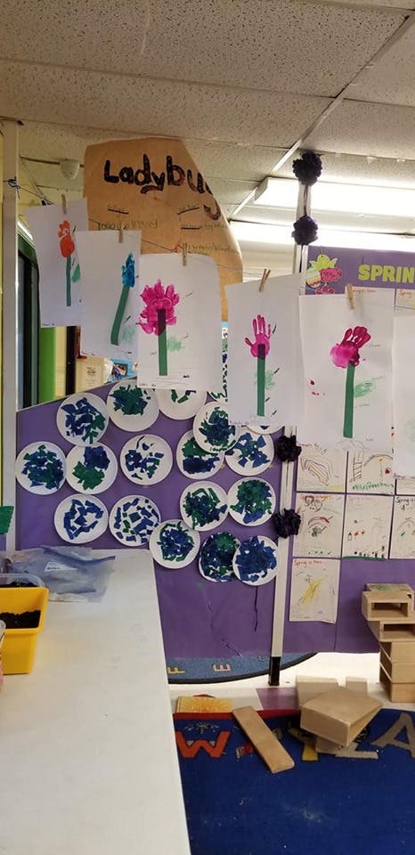 Children's artwork displayed on a purple board in a classroom