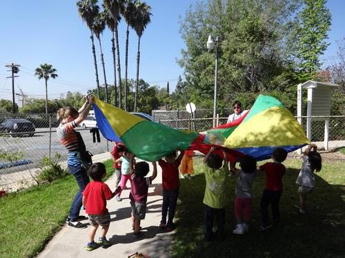 Adults and children playing with a colorful parachute outdoors