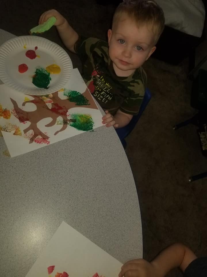 Child painting a tree with green and red paint