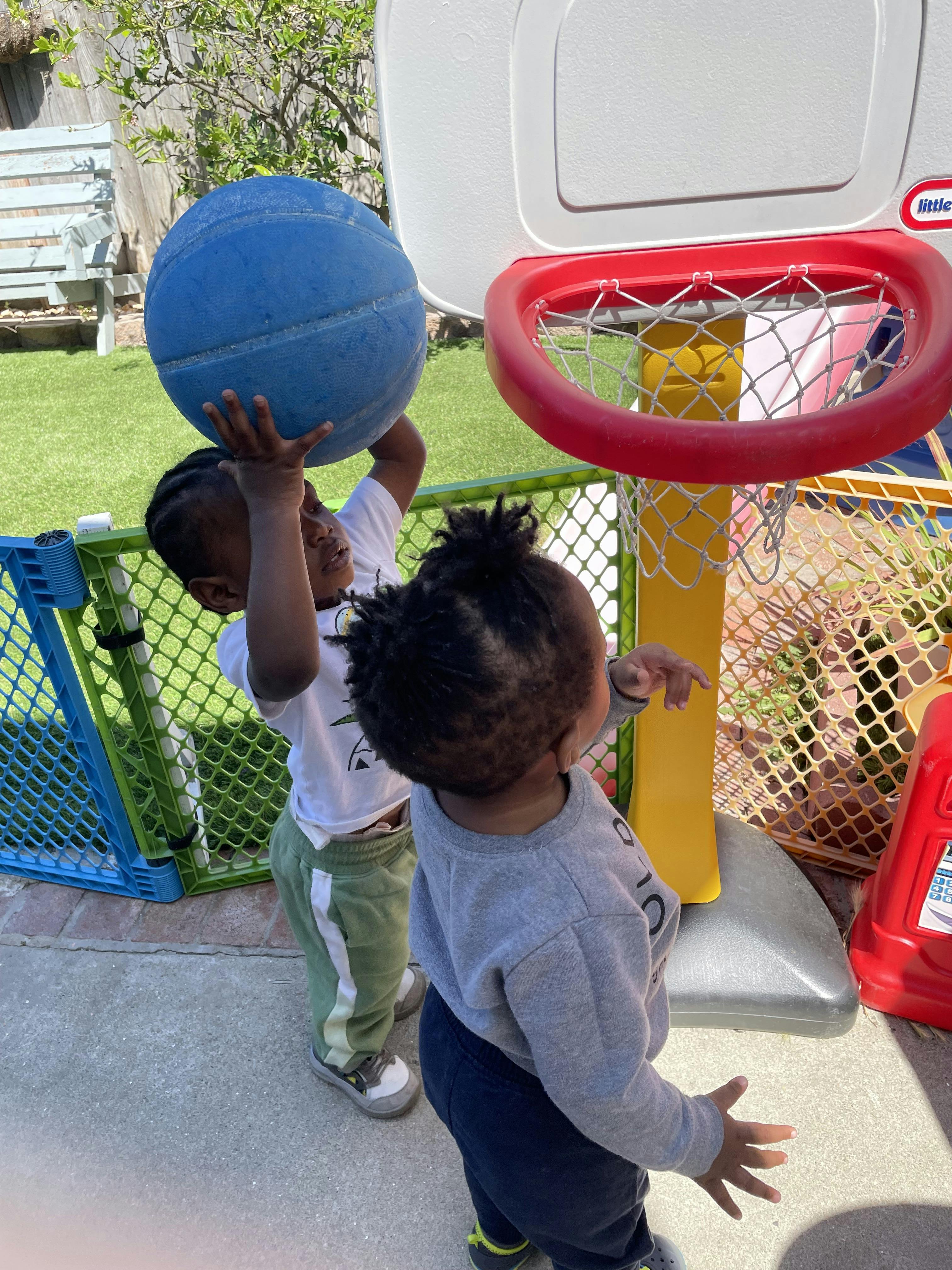 Child holding a basketball over their head near a basketball hoop