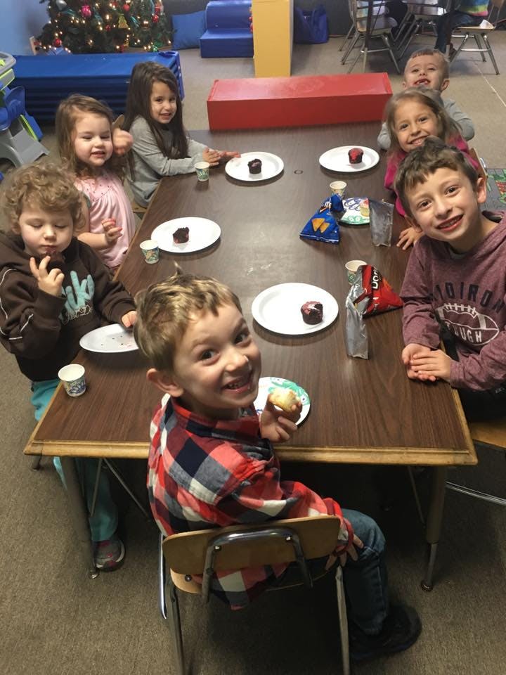 Children sitting around a table with cupcakes