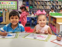 Two children drawing at a table in a classroom
