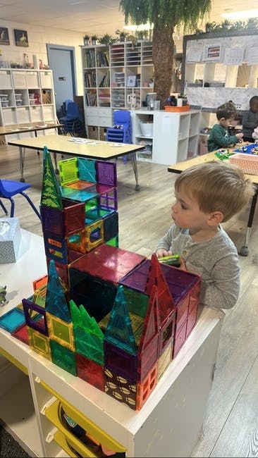 Child looking at a colorful building made of magnetic tiles in a classroom