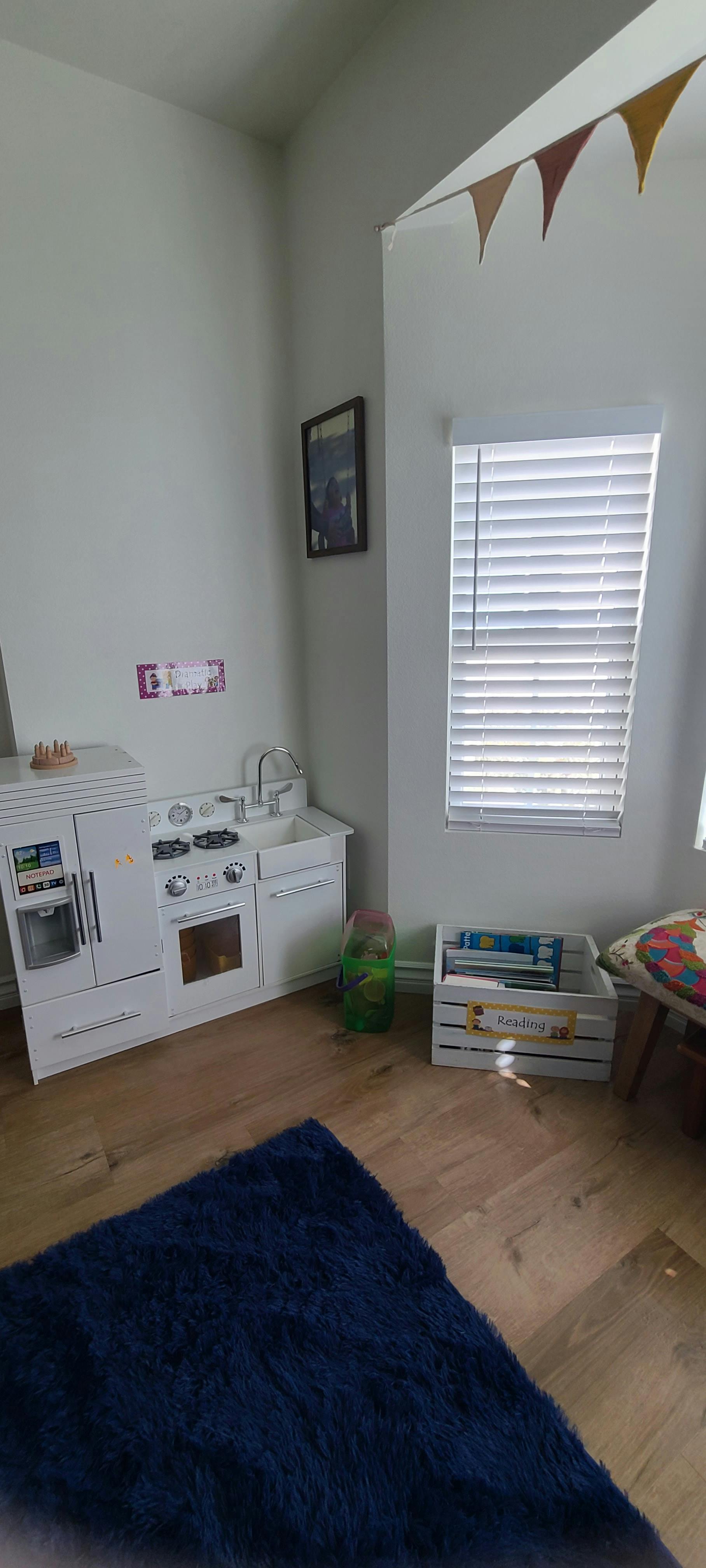 Play kitchen set with a blue rug on a wooden floor