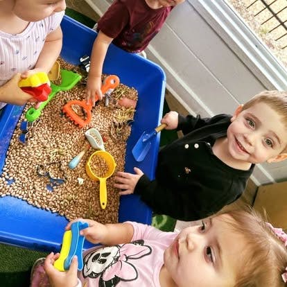 Children playing with sensory bin filled with beans and toys