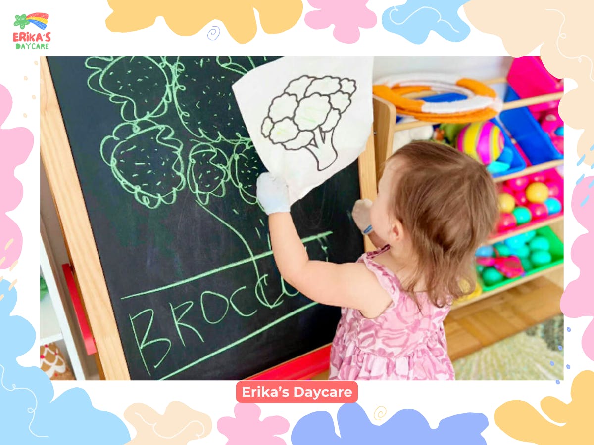 Child drawing a broccoli illustration on a chalkboard