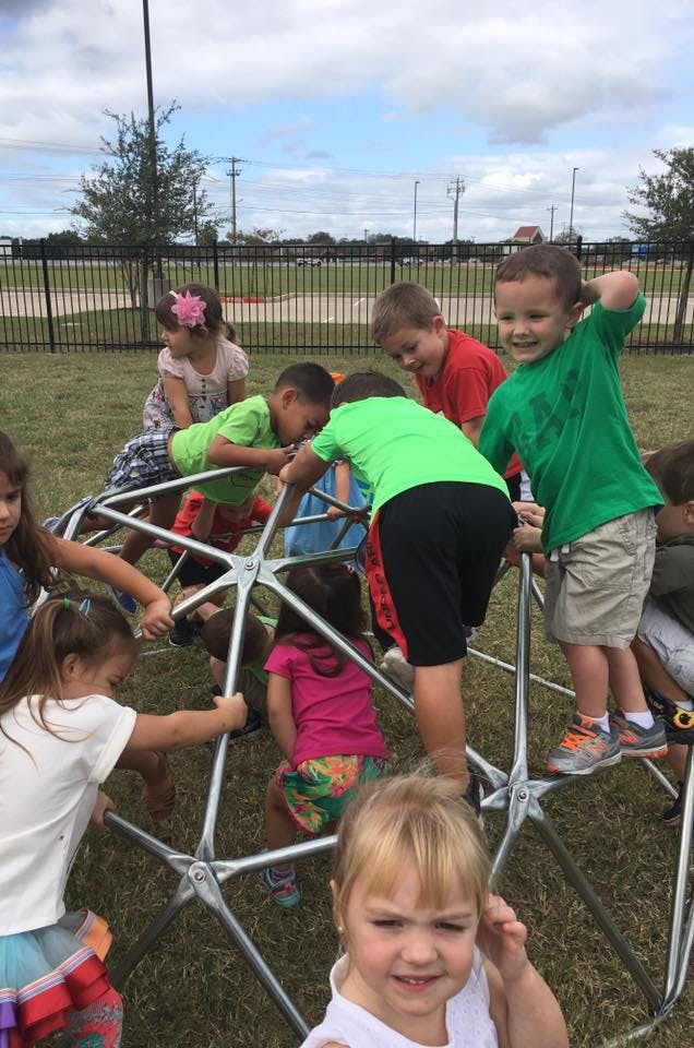 Children playing on a metal dome climber on a playground