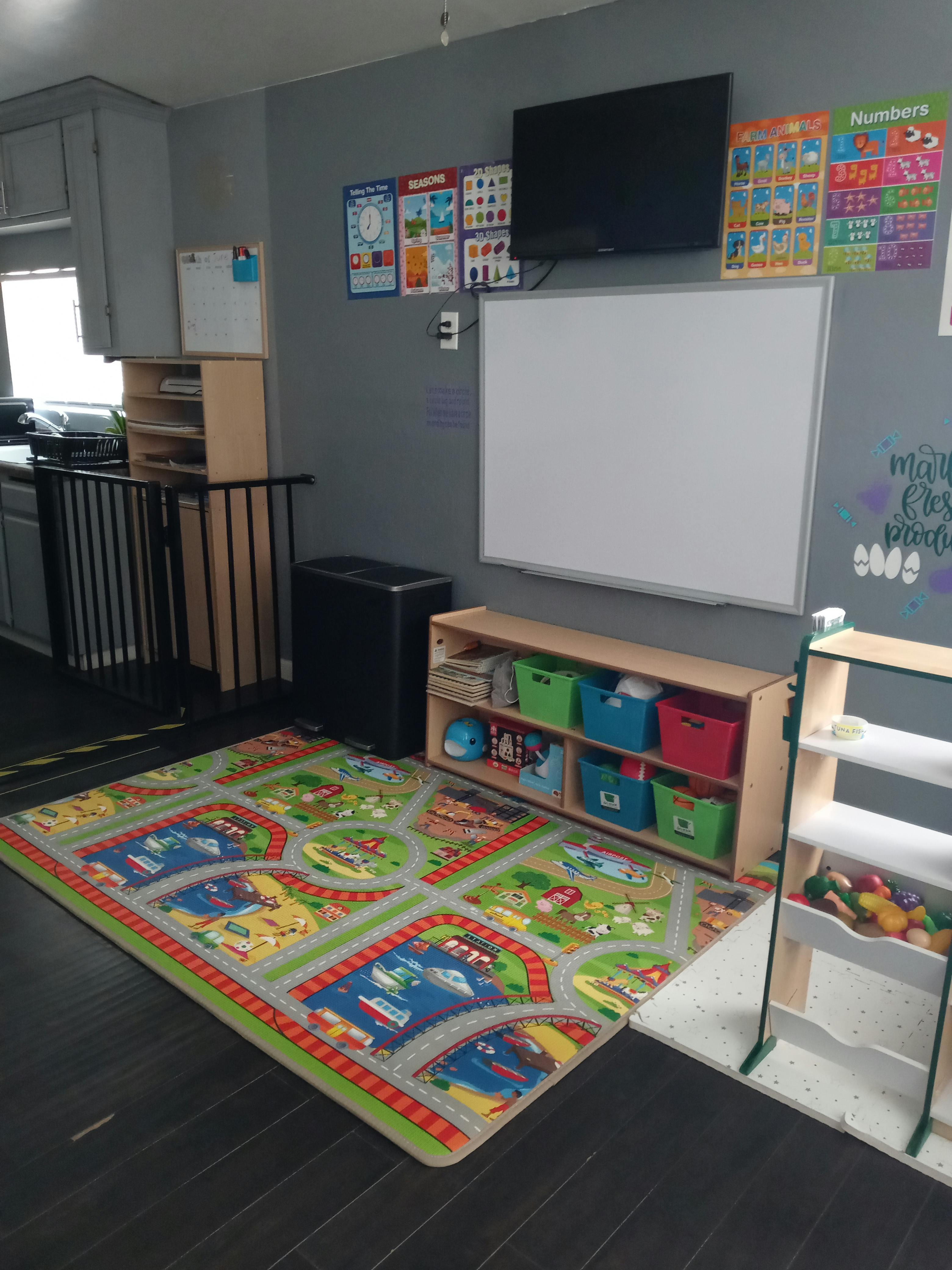 Playroom with a colorful rug, shelves with toys, and a whiteboard