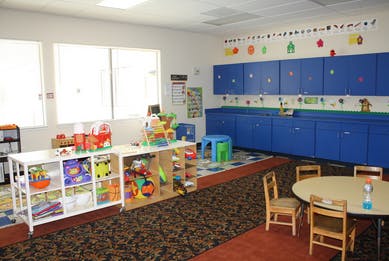 Classroom with toys, blue cabinets, and small tables